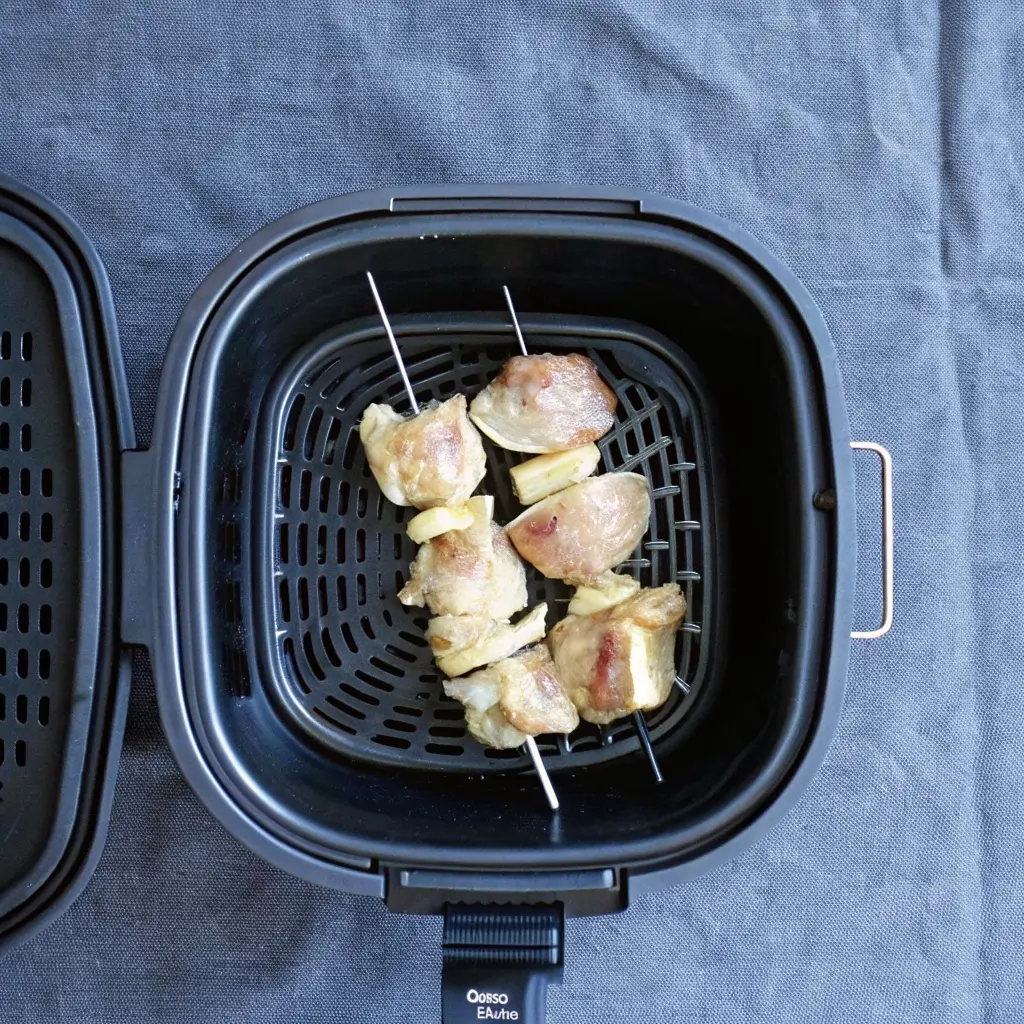 Hähnchenspieße mit Zwiebelstücken in einer Heißluftfritteuse bereit zum Braten.