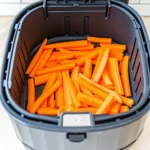 Geschnittene Möhrenstreifen in einem Airfryer-Korb bereit für die Zubereitung – frisch, knackig und perfekt portioniert für knusprige Möhren in der Heißluftfritteuse.