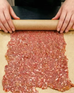 Zubereitung des Backpapier-Döner im Airfryer: Hackfleisch wird mit einem Nudelholz flach ausgerollt