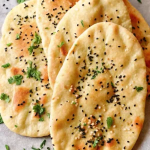 Naan Brot servieren: Mehrere goldbraune indische Fladenbrote mit schwarzem und weißem Sesam sowie Kräutern bestreut, kunstvoll gestapelt